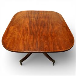 Regency figured mahogany breakfast table, figured rectangular tilt-top with rounded corners and rosewood banding, on turned column with four out-splayed supports with brass cups and castors 