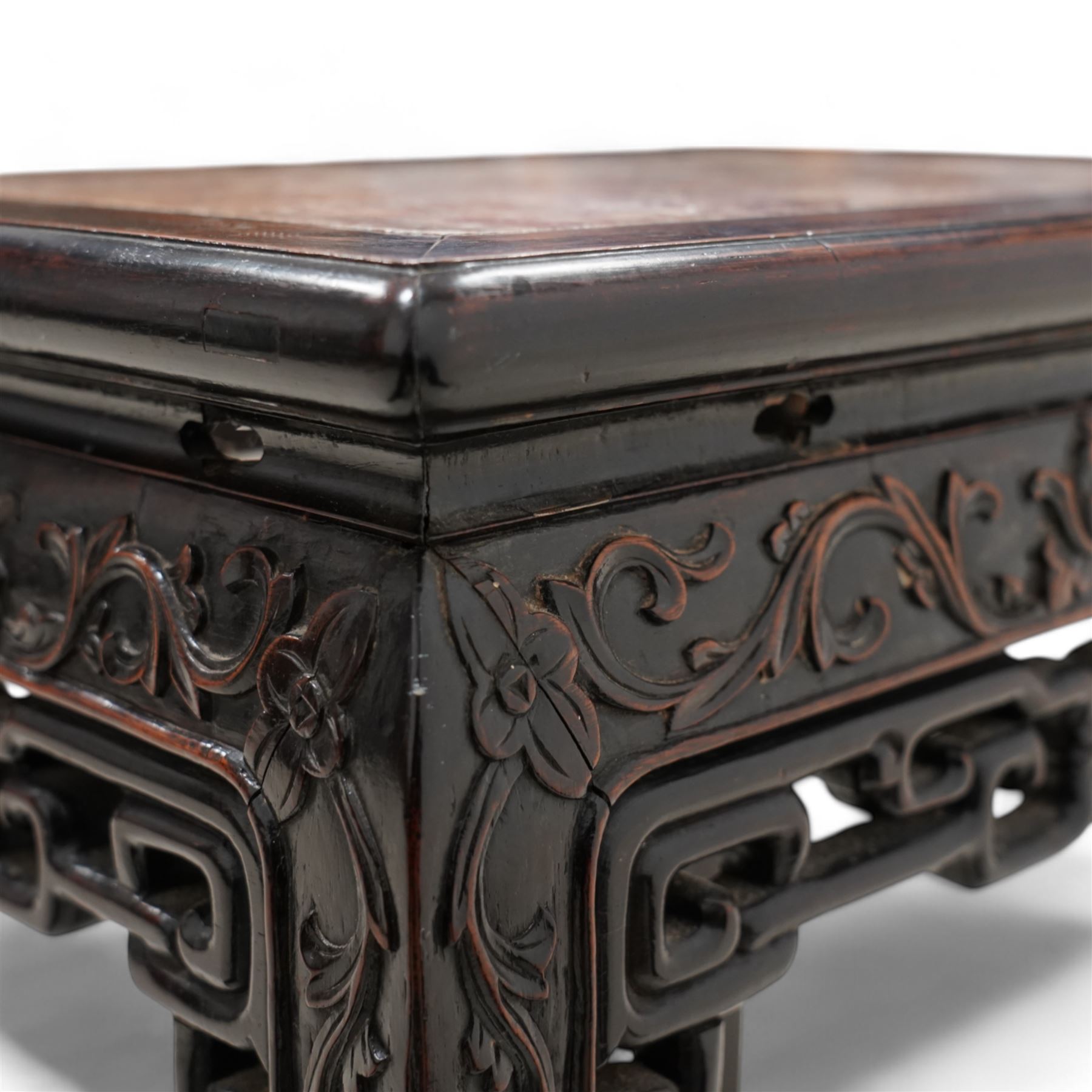 Early 20th century Chinese carved hardwood and marble urn stand, rectangular moulded top with inset variegated rouge marble, carved with curling leafy branches and scrolls, shaped and pierced brackets, on ball and claw carved supports 