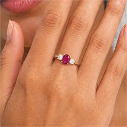 18ct gold ruby and diamond three stone ring, single oval cut ruby of 1.06 carat, with a round brilliant cut diamond set either side, hallmarked, total diamond weight 0.31 carat