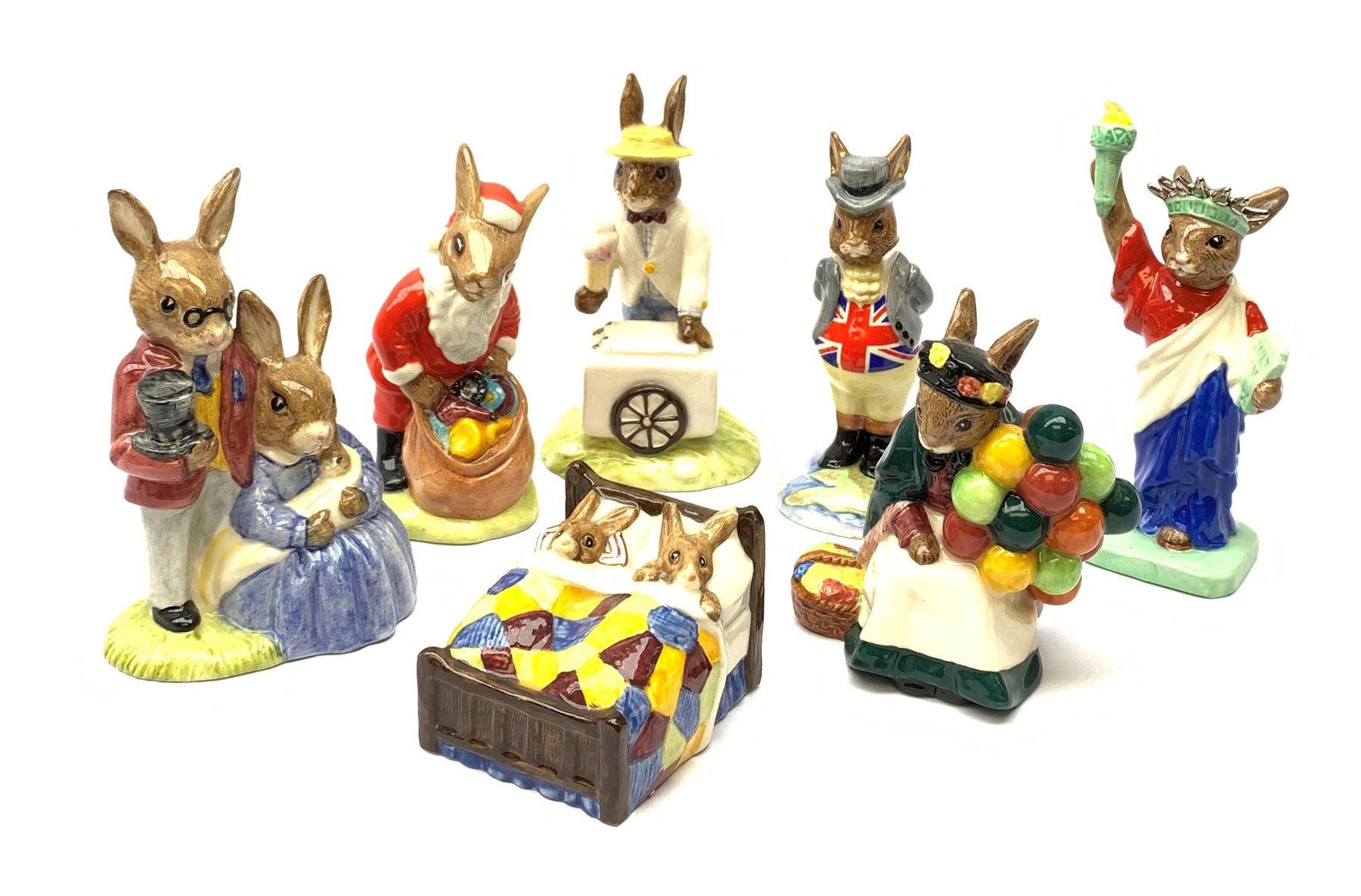 A group of seven Royal Doulton Bunnykins figures, comprising Father, Mother & Victorian Bunnykins DB68, Santa Bunnykins DB17, Uncle Sam Bunnykins DB50, Bunnykins Sleepytime DB15, Old Baloon Seller Bunnykins DB217, Statue of Liberty Bunnykins DB198, and Ice Cream Bunnykins DB82.