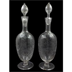 Pair of Edwardian Stourbridge style glass claret decanters and stoppers, of ovoid form with tall tapering necks, supporting hollow stoppers, the bodies and stoppers etched with fruiting vines, upon folded circular feet, H13.5cm