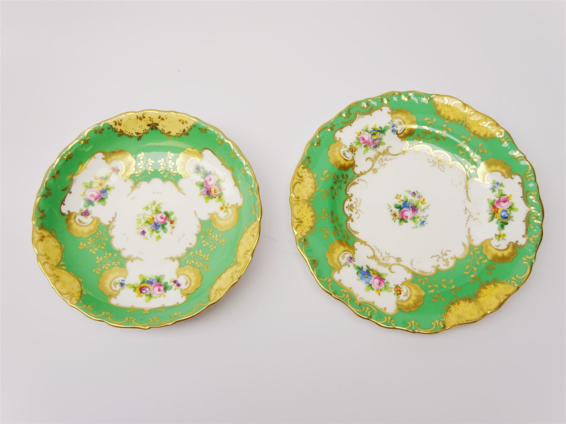 19th century Minton tea set, comprising twelve teacups, eleven saucers, fifteen side plates, cream jug, slop bowl, and two cake plates, decorated with panels of floral sprays, upon a green ground, heightened with gilt throughout, with printed puce mark beneath, and pattern number 5329
