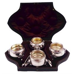 Set of four Victorian silver Egyptian Revival open salts, each of cauldron form with engraved key fret border, and beaded rim, three with clear glass liners, upon three pharaoh mask mounted feet, together with four spoons of conforming design, hallmarked Hilliard & Thomason, Birmingham 1880, contained within a fitted case with burgundy velvet and silk lined interior, approximate silver weight 7.67 ozt (238.7 grams)