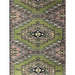 Pakistani olive and rose ground runner rug, the field decorated with repeating hexagonal medallions, surrounded by a rose-hued field with repeating diamond patterns, the borders featuring geometric motifs and trailing foliate designs