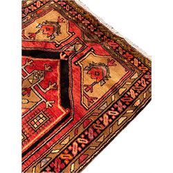 Persian Karajeh red ground runner, the field set with three trailing geometric medallions, decorated all over with stylised plant motifs, geometric design triple band border
