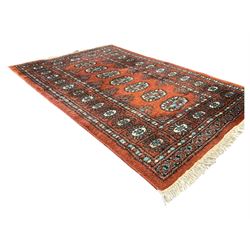 Pair of rugs one Persian hamadan rug central stepped medallion enclosing geometric motifs in ivory and brown, framed by a cream border with scrolling palmettes and fringed ends (H 156cm W 105cm), one Pakistani Bokhara rug rust red ground with repeated Tekke gul motifs within rosette and lozenged borders, fringed ends (H 98cm, W 65cm)