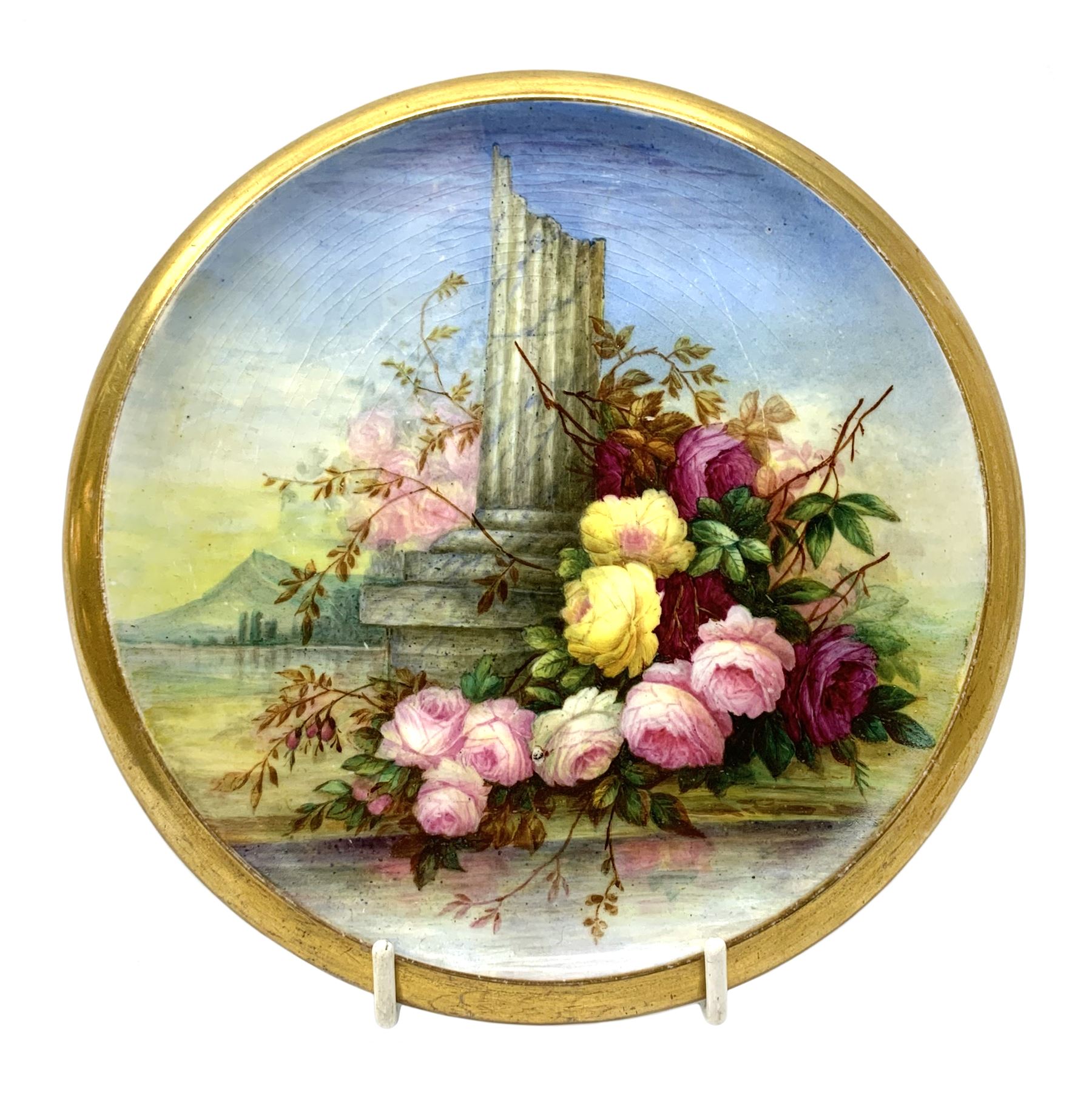 19th century porcelain stand, of circular form, in the Derby style, hand painted with a ruinous column and roses against a landscape background, within a gilt border, D7cm