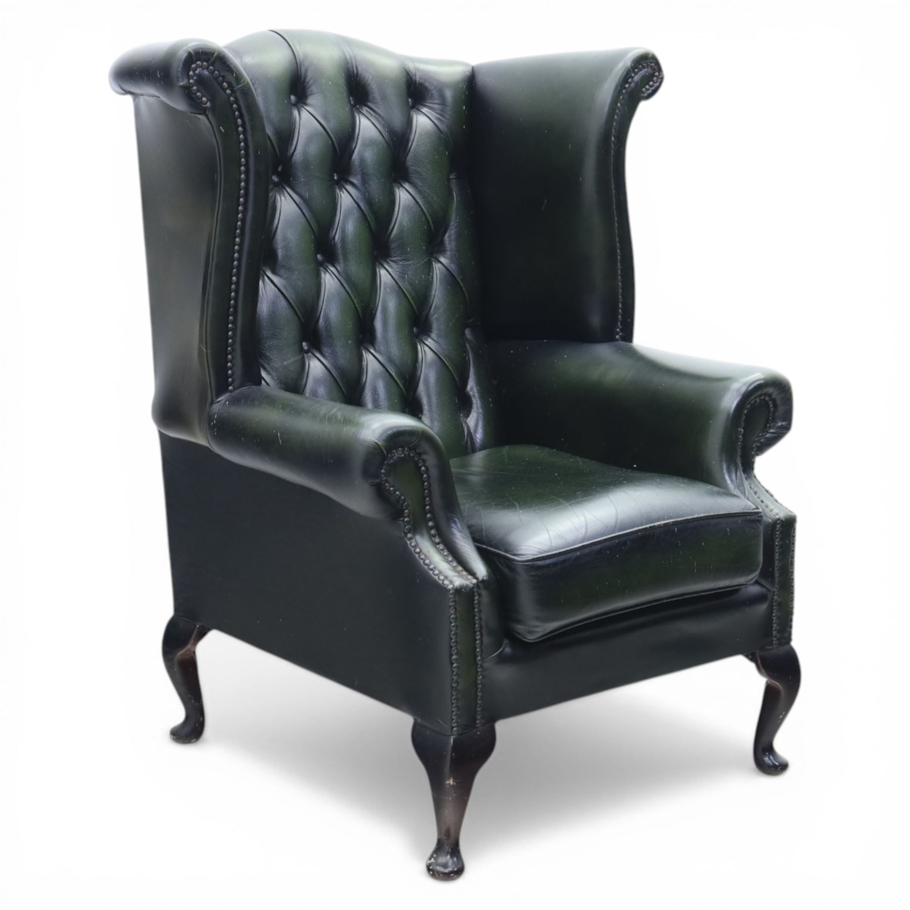 Late 20th century green leather chesterfield style wingback armchair, with deep buttoned back, scrolled wings and arms with studded borders, loose seat cushion, raised on cabriole legs