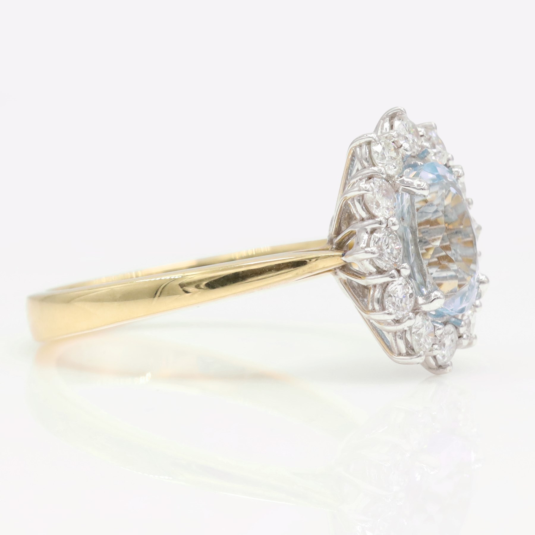 18ct gold aquamarine and diamond cluster ring, single oval cut aquamarine of approx 1.25 carat, surrounded by twelve round brilliant cut diamonds, hallmarked, total diamond weight approx 0.30 carat