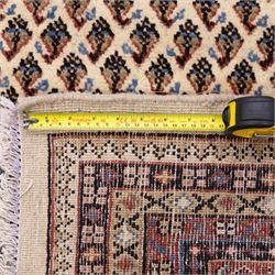 West Persian Botteh-Mir hand-knotted rug, ivory field decorated with an overall dense lattice design of small repeating boteh motifs in muted blue, rust, and brown tones, enclosed by a series of narrow borders incorporating stylized geometric and floral patterns with cotton fringe ends 