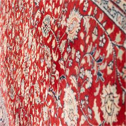 Persian crimson ground rug, interlacing floral stems linking ivory palmettes, rosettes and serrated leaves, within a navy floral border flanked by ivory patterned guards
