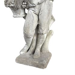 Haddonstone - weathered cast stone garden statue of a boy holding a basket of grapes, modelled with curled locks of hair wearing a tunic and breeches leaning against a naturalistic tree stump, on square base