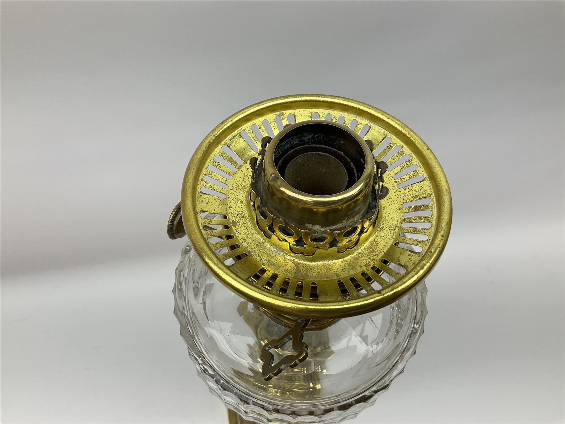 Victorian brass oil lamp, the square stepped base leading to a Corinthian column supporting a part slice cut clear glass reservoir, burner, clear glass chimney and foliate etched glass shade with amber rim, overall H80cm