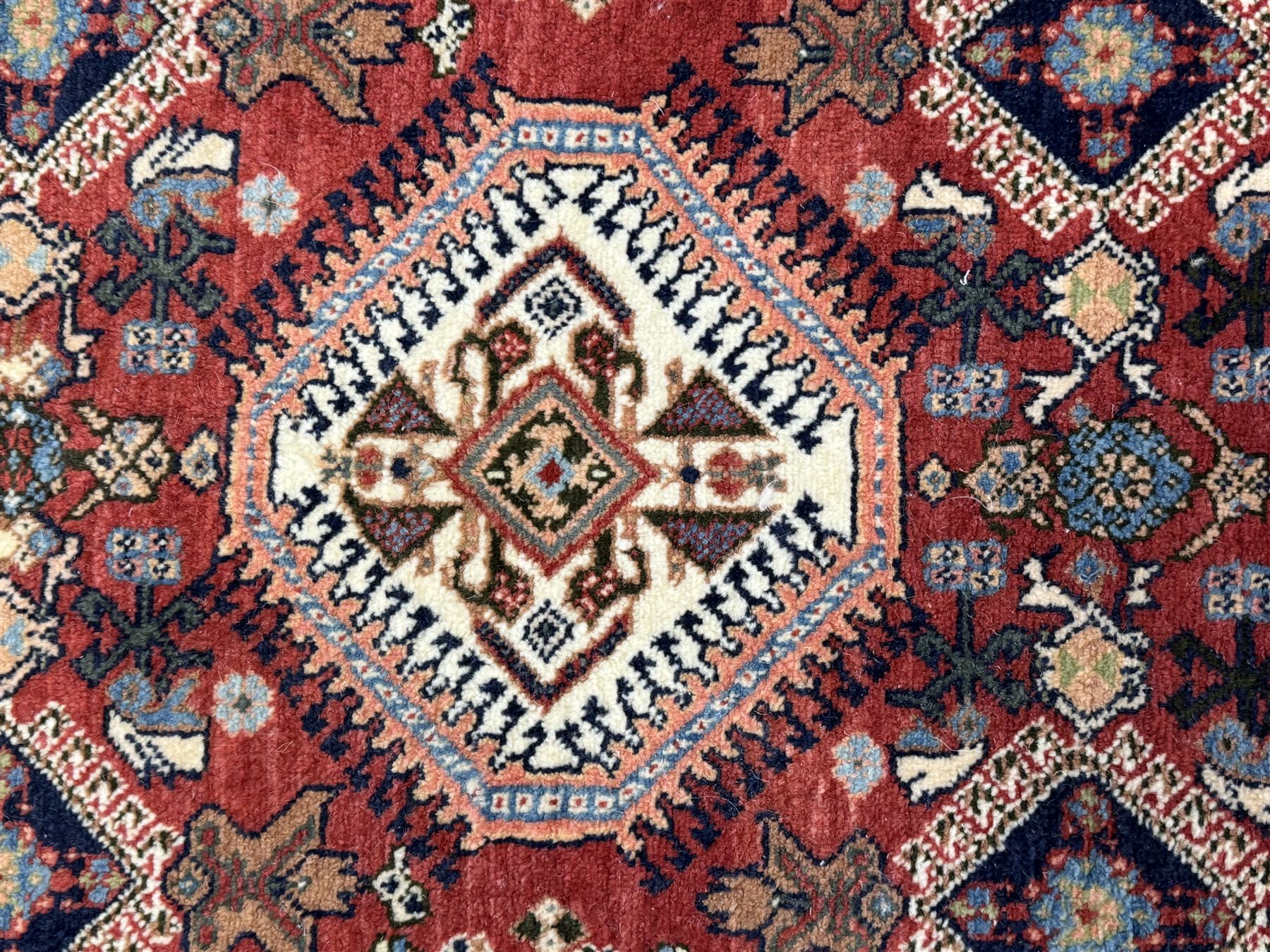 Pair of rugs one Persian hamadan rug central stepped medallion enclosing geometric motifs in ivory and brown, framed by a cream border with scrolling palmettes and fringed ends (H 156cm W 105cm), one Pakistani Bokhara rug rust red ground with repeated Tekke gul motifs within rosette and lozenged borders, fringed ends (H 98cm, W 65cm)