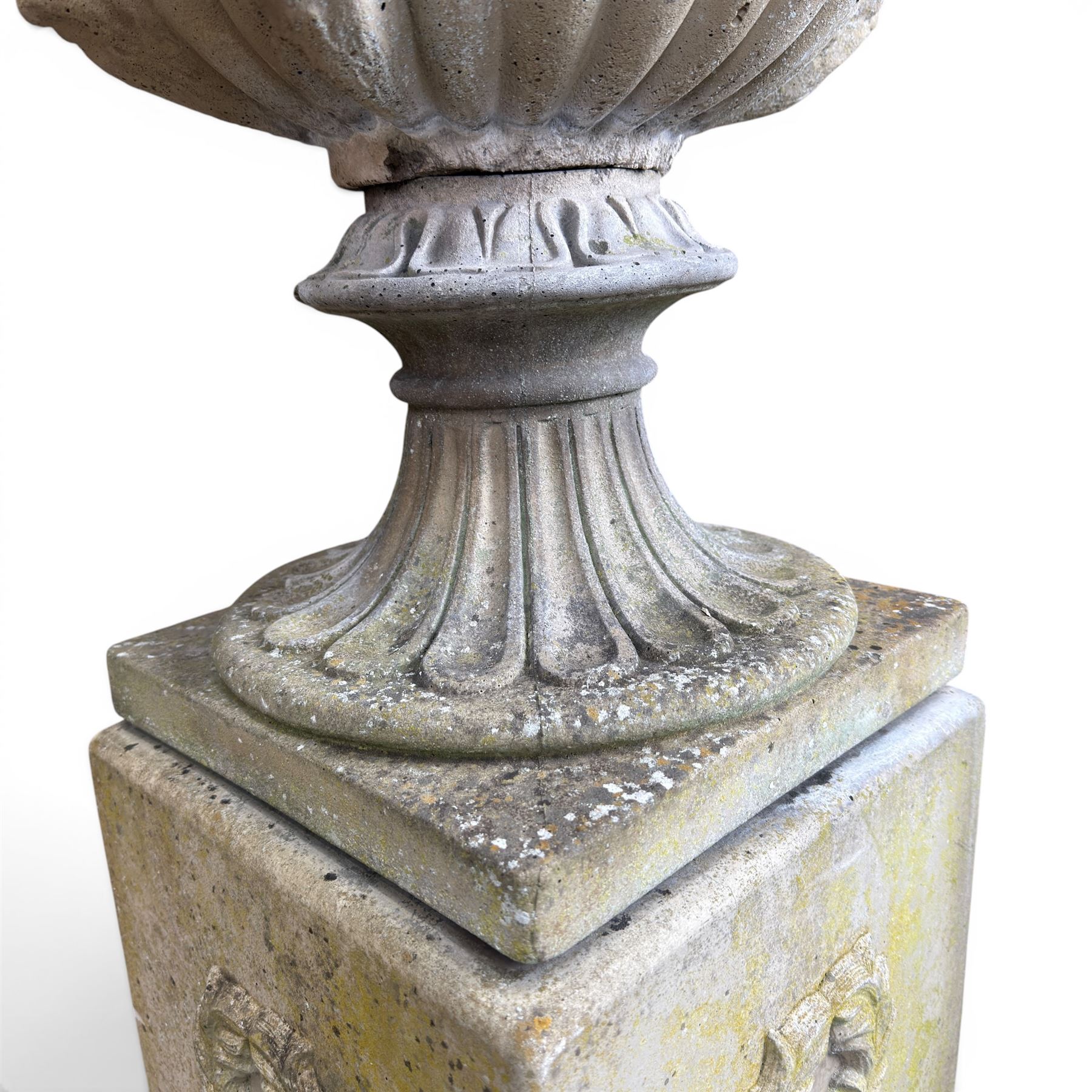 Cast stone classic garden urn, the rim decorated with leaves and berries, twin handles with face masks, raised on square base, stamped HGC