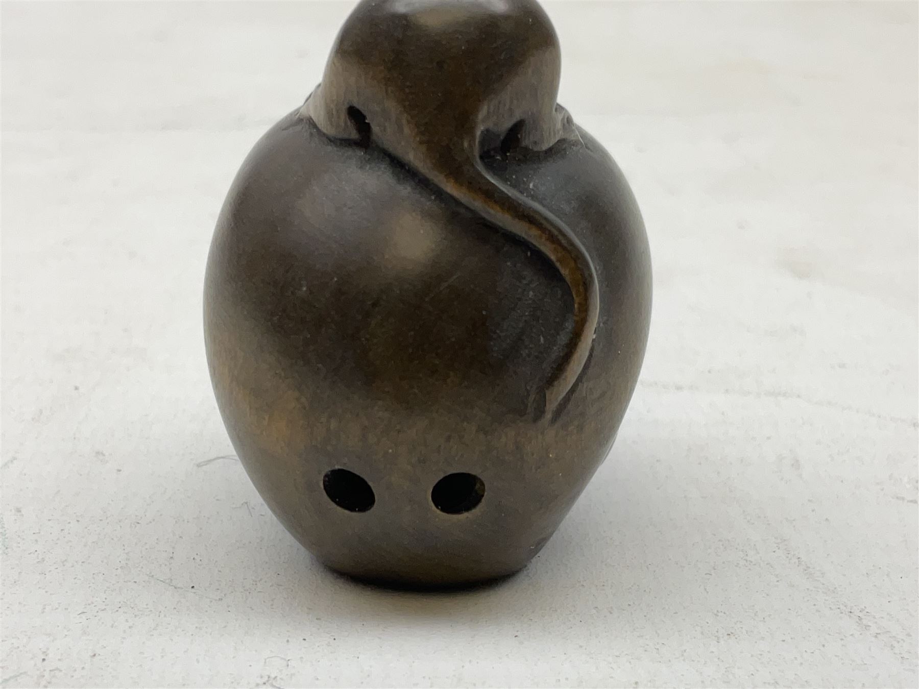 Netsuke in the form of a rat sitting on a skull, signed to the base