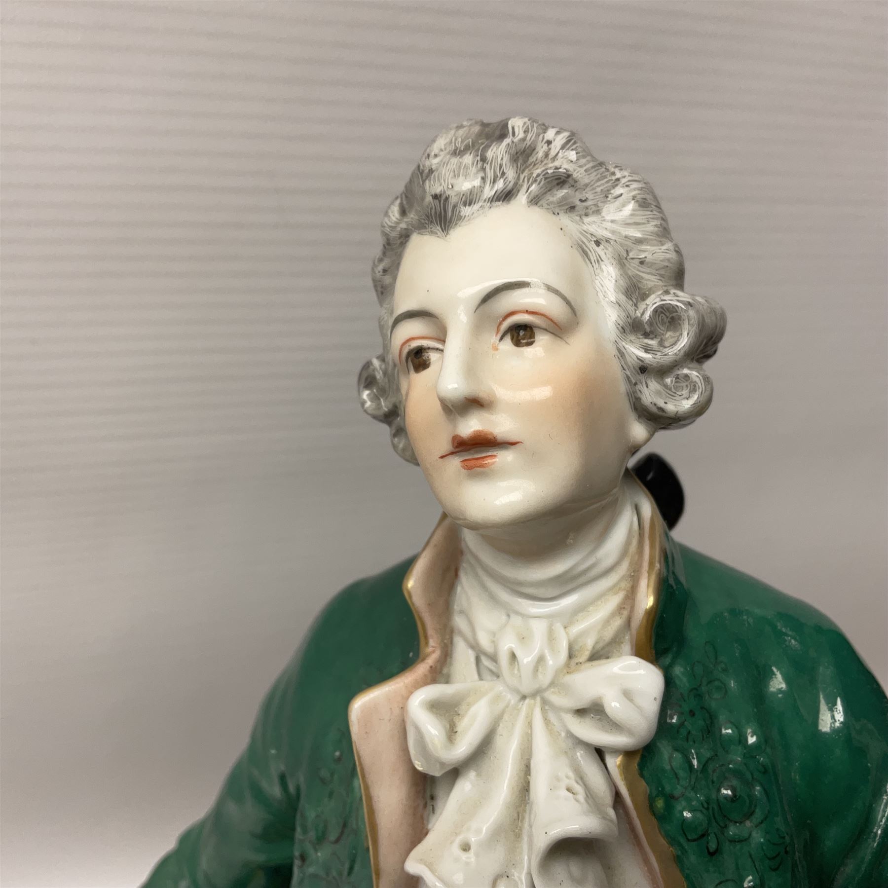 20th century Naples figure group, modelled as a seated female figure playing the lute seated, before a male figure stood holding a sheet of music, each in period dress, upon an oval base with gilt heightened scroll edge, with crowned N mark beneath, H31.5cm L33cm
