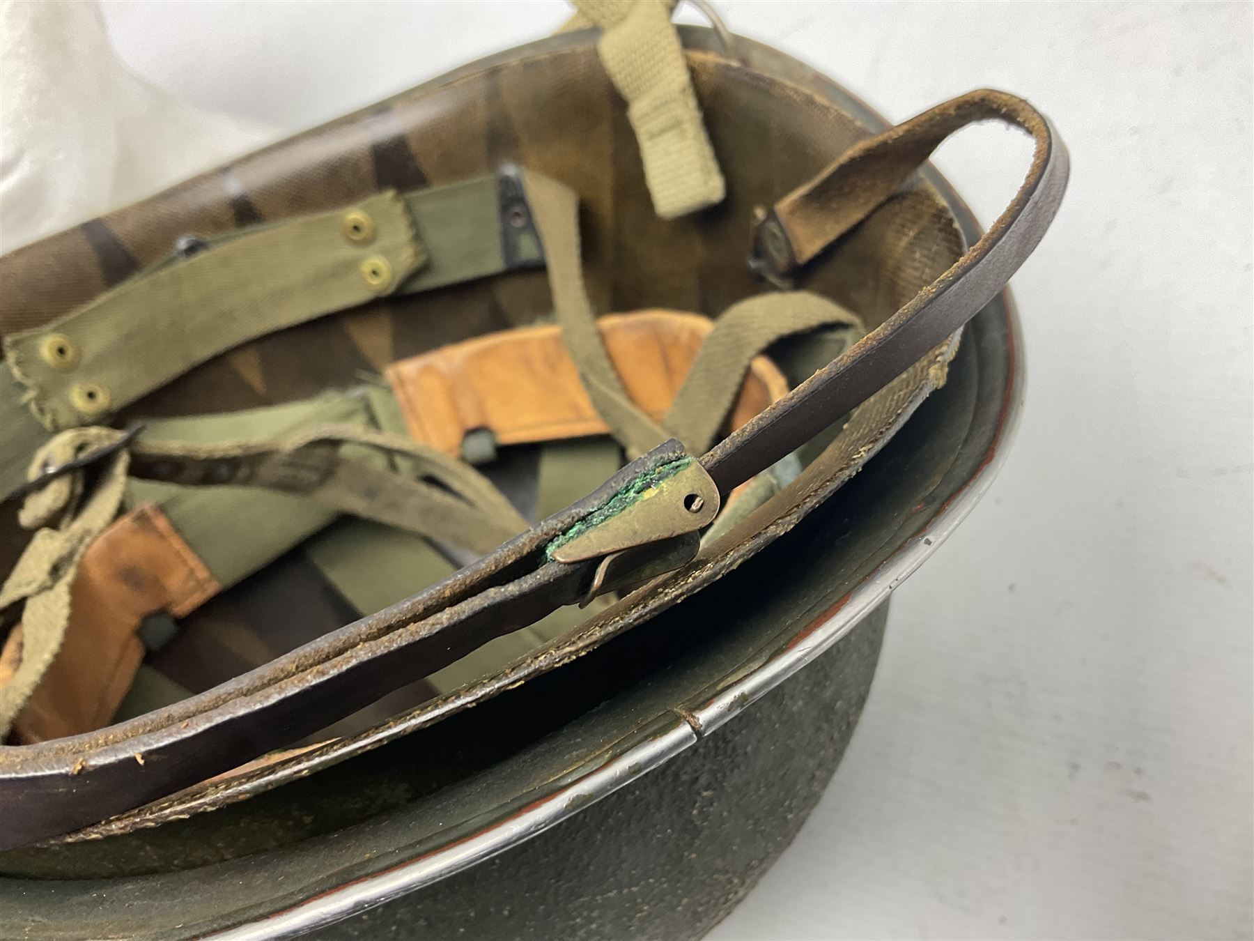 American first type paratrooper helmet with post-WW2 strap and D-rings and later 1944 liner bearing Firestone Tyre and Rubber Company mark; green textured finish