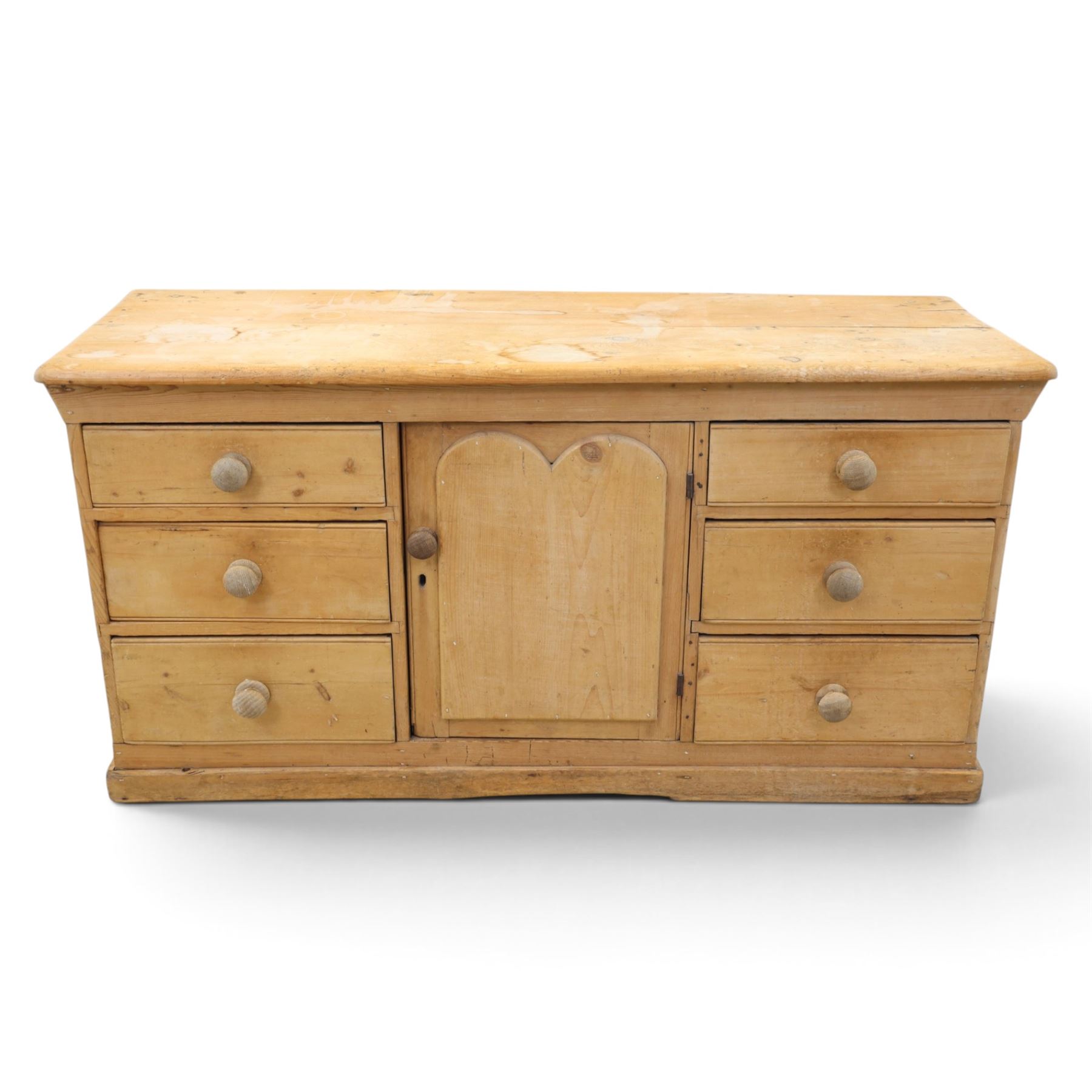 Victorian stripped pine sideboard, rectangular plank top rounded edges, with central cupboard door with shaped panel, flanked by two banks of three graduating drawers with turned knobs, raised on a plinth base 