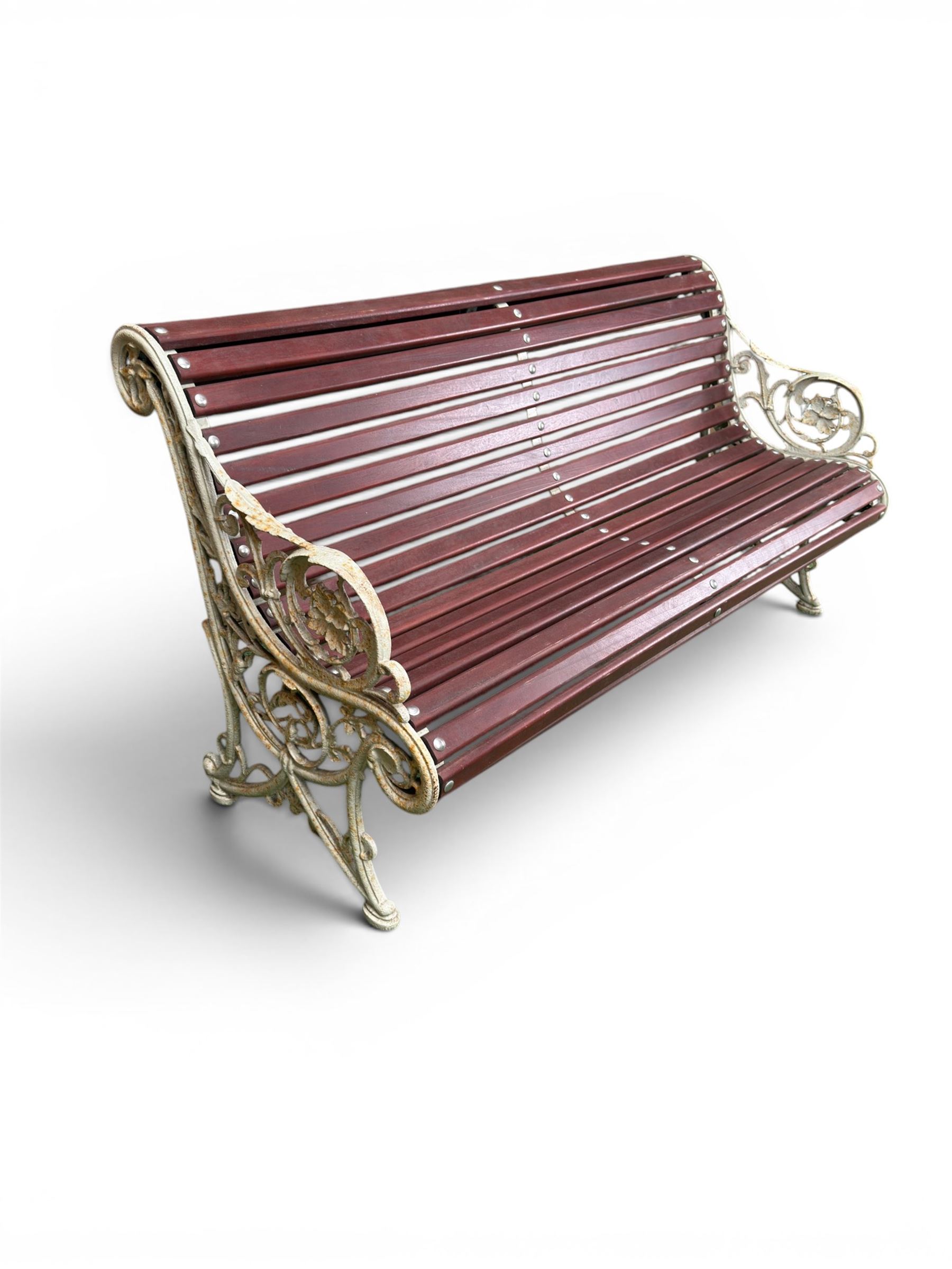 Large late Victorian cast iron garden bench, serpentine form with scroll back and seat, slatted with mahogany stained Sapele