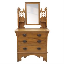 Edwardian stained pine dressing chest, the moulded top over three graduating drawers with pressed brass handles, shaped apron and bracket feet, the mirror back with rectangular plate on pivot supports, flanked by pierced Gothic style uprights with small corner shelves