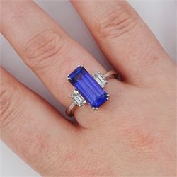 Platinum tanzanite and diamond three stone ring, single emerald cut tanzanite of approx 4.20 carat, with with a single trapeze cut diamond set either side, stamped PT950, total diamond weight approx 0.49 carat, with Alan Poultney Gems report