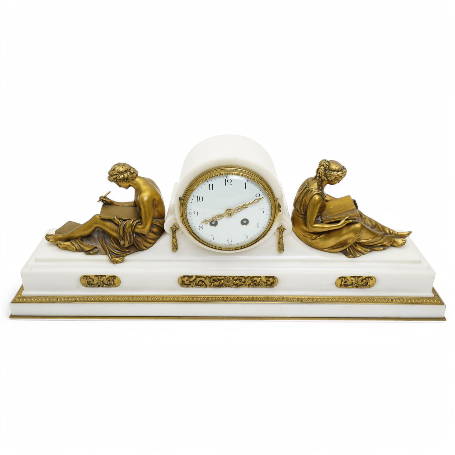 French- Fine early 20th century 8-day white marble mantle clock, on a rectangular stepped plinth with recessed brass banding and inset oval brass panels with raised scroll and leaf decoration, drum cased Parisian  movement flanked by a pair of seated cast brass figures taken from classical antiquity, with a convex white enamel dial and glazed cast brass bezel, Arabic numerals and minute markers with matching pierced brass hands, twin train going barrel movement with a recoil anchor escapement and rack striking, sounding the hours and half hours on a bell. With pendulum.  