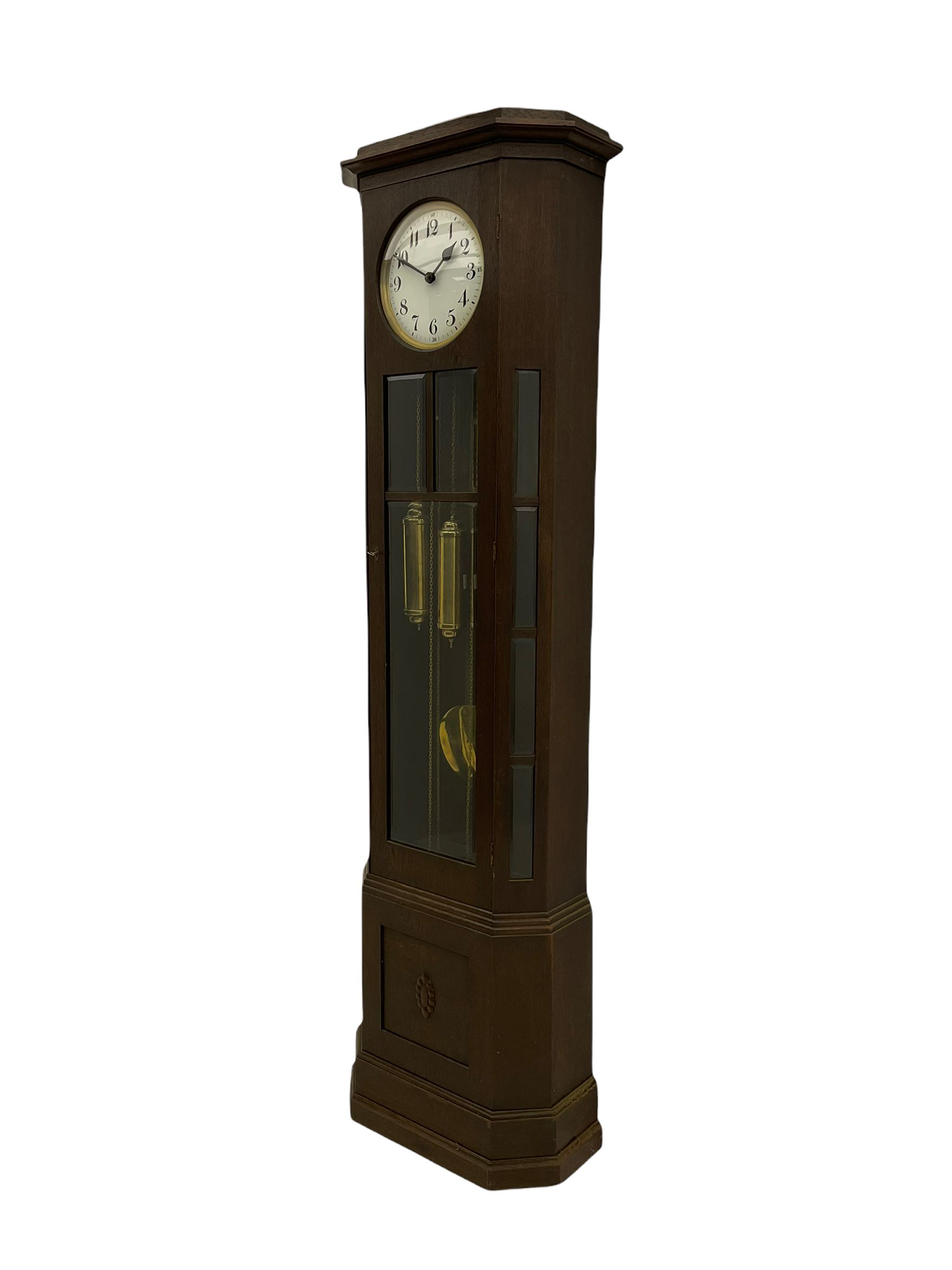 A mid-20th century weight driven floor standing clock in an oak case with canted glazed panels, full length glazed trunk door on a rectangular plinth with applied double skirting, white enamel dial with a gilt slip, upright Arabic’ numerals, minute markers, quarter hour Arabic’s and steel spade hands, with a three-train weight driven Westminster chiming movement chiming on two sets of gong rods.
With pendulum and weights.

