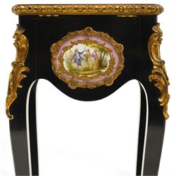 Early 20th century French ebonised sewing or work table, rectangular hinged top with foliate moulded gilt metal edge, enclosing upholstered interior, over a central Sevres style porcelain plaque depicting a courting scene, raised on cabriole supports with gilt metal carotuche and acanthus knee mounts, united by undertier with brass gallery terminating to gilt metal scroll feet