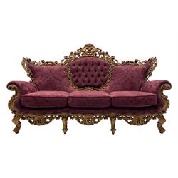 Late 20th century Italian style carved beech framed three seat sofa and pair matching armchairs, the framed carved and pierced with scrolling acanthus leaves and flower heads, cabriole supports, upholstered in buttoned claret fabric with raised foliate pattern 