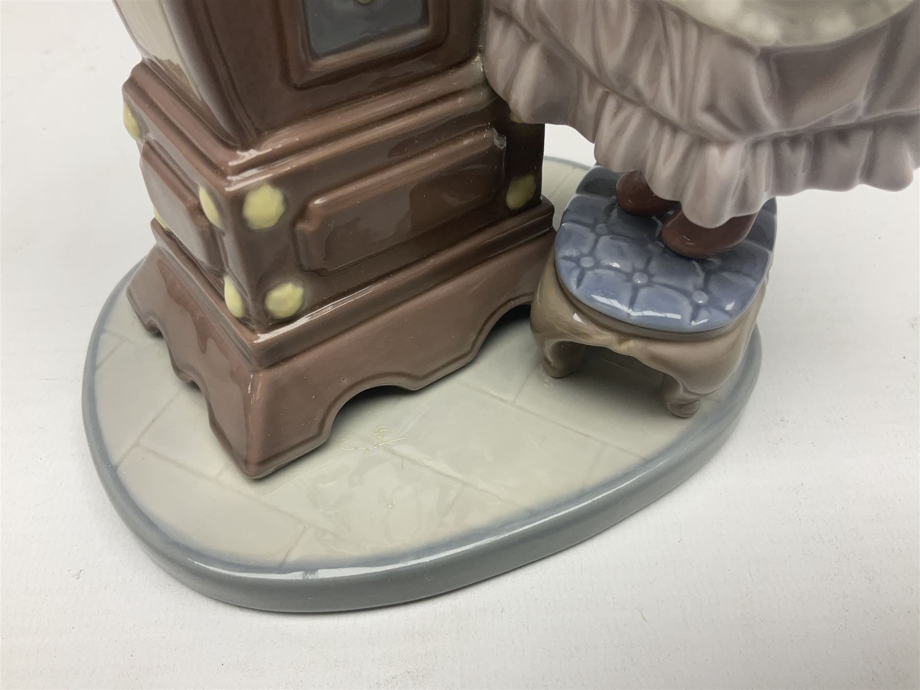 Lladro figure, Bedtime, modelled as a young girl reaching for her pet cat upon grandfather clock, sculpted by Vincente Martinez, with original box, no 5347, year issued 1986, year retired 1998, H28cm