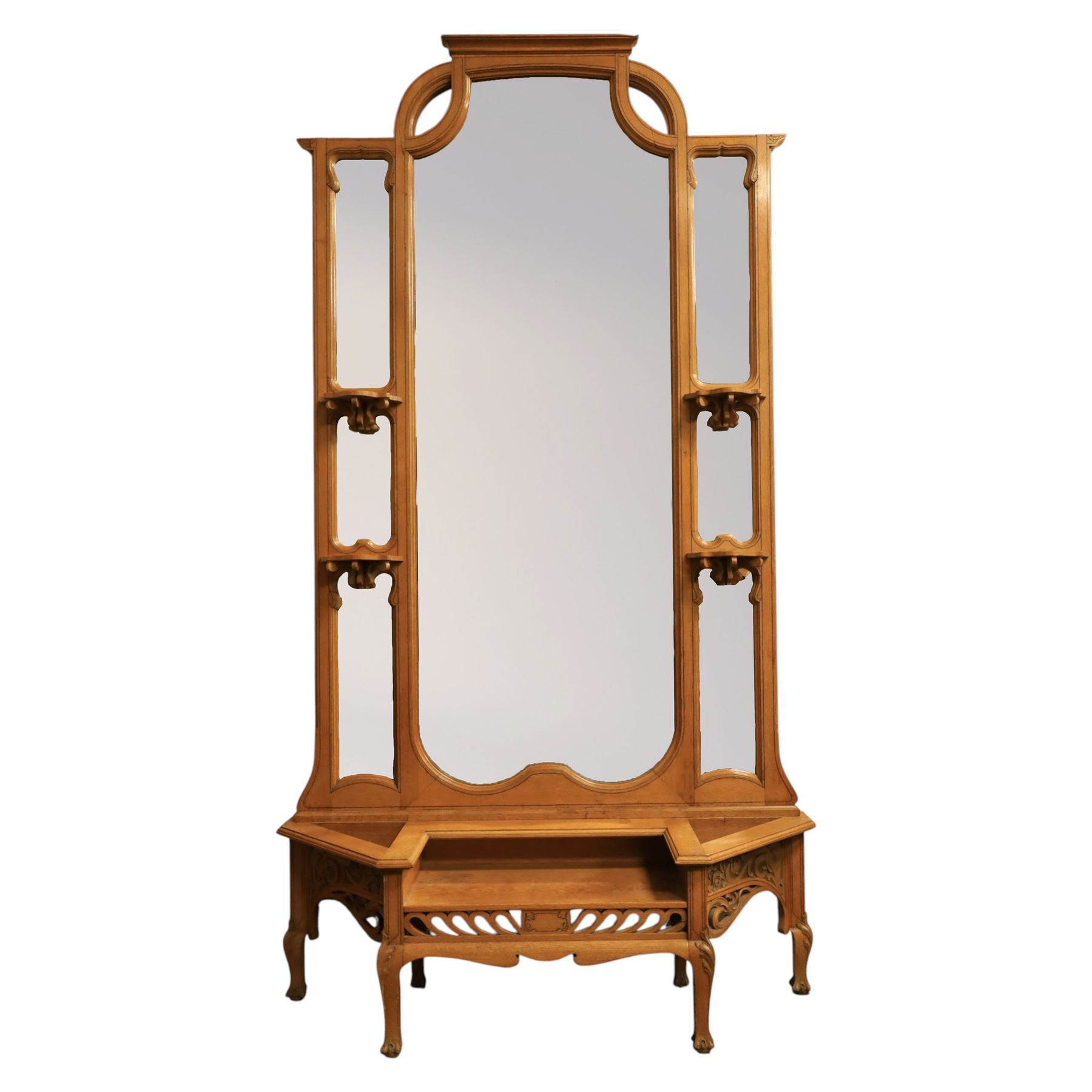 Art Nouveau oak hall mirror, the scrolling frame with large central bevelled mirror plate, boardered by six small mirrors with four shelves between, the base, with carved and pierced floral decoration, upon six cabriole legs   