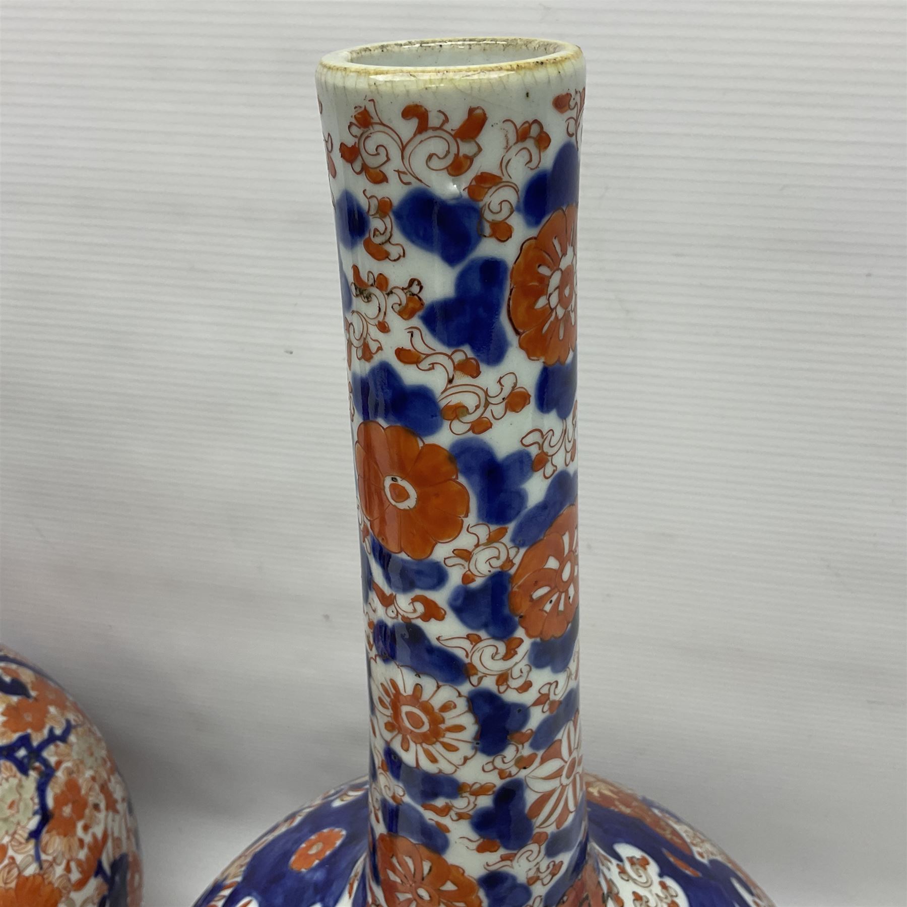 Pair of large 19th century Japanese Imari porcelain bottle vases, painted with shaped reserves of peonies, chrysanthemums and prunus blossom, each H46cm