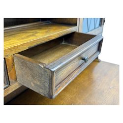 Large mid-20th-century oak dresser with two astragal glazed doors between gallery shelf and lower shelf, with three short drawers and lower section with four drawers and three double-panelled linen-fold hinged cupboard doors 