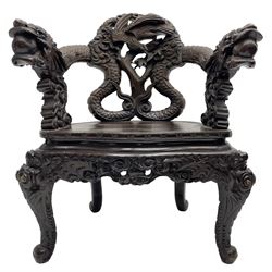 Japanese Meiji period open armchair, the back carved and pierced with dragon and scrolling scaled tails, projecting dragon carved arm terminals on scrolled supports, serpentine seat with decorative band, the apron and supports with scroll and chip-carved decoration
