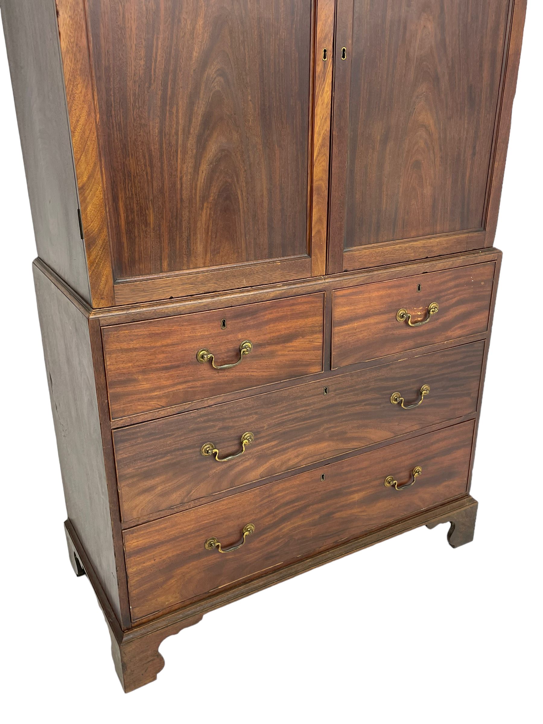 George III mahogany Gentleman's linen press, the projecting cornice over two panelled cupboard doors enclosing three sliding trays, the base fitted with two short over three long graduating cock-beaded drawers, lower moulded edge over bracket feet