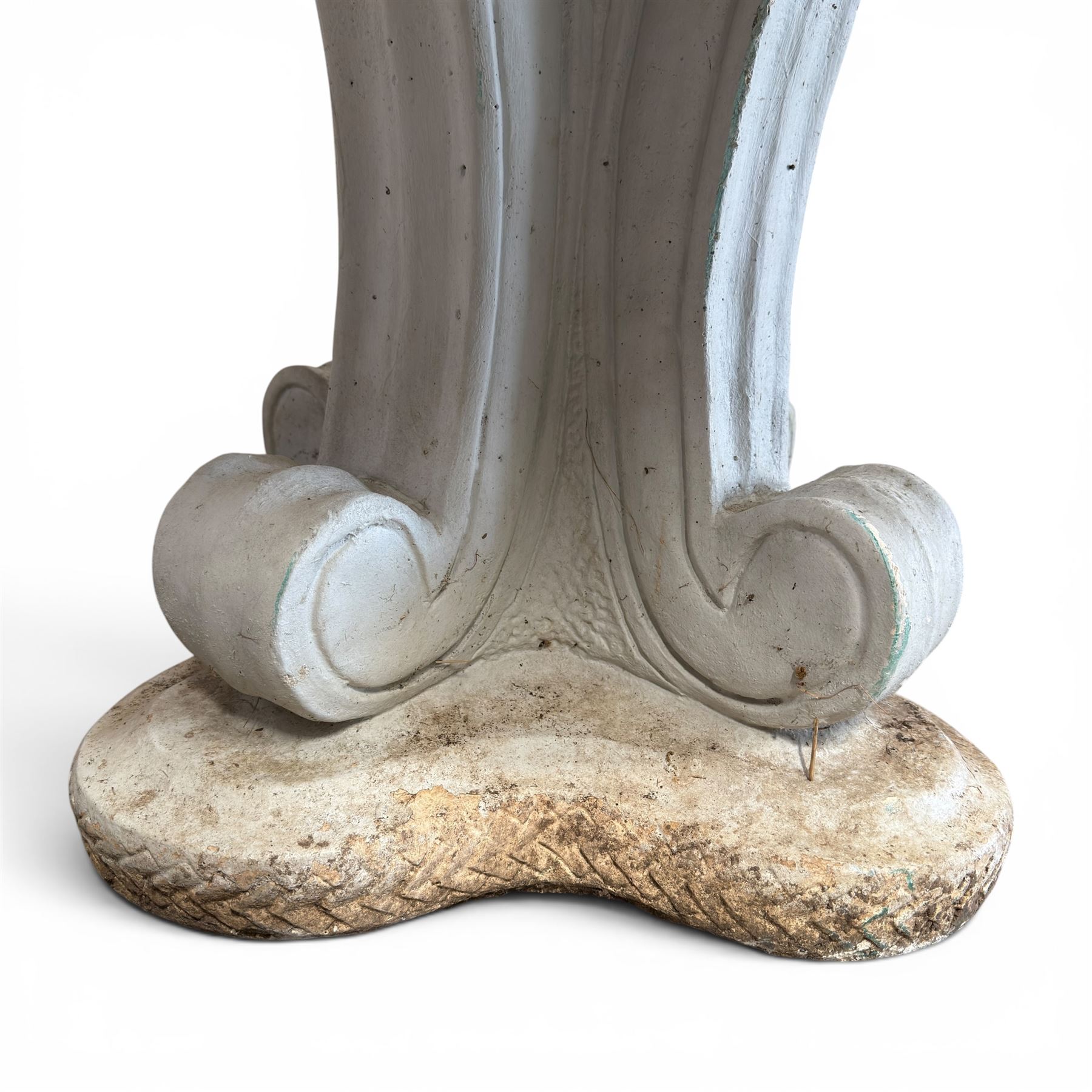 Weathered cast stone garden table, circular top etched with central floral medallion, the edge with repeating chevron motifs, raised on a quadriform S-scroll pedestal with stepped and chevron carved base