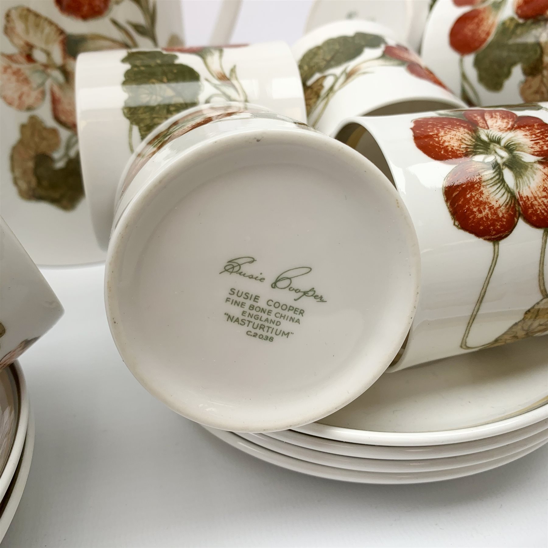 A Susie Cooper Nasturtium pattern tea service, comprising tea pot, coffee pot, six tea cups and six saucers, six coffee cans and six saucers, six side plates, milk jug, and lidded sucrier. 