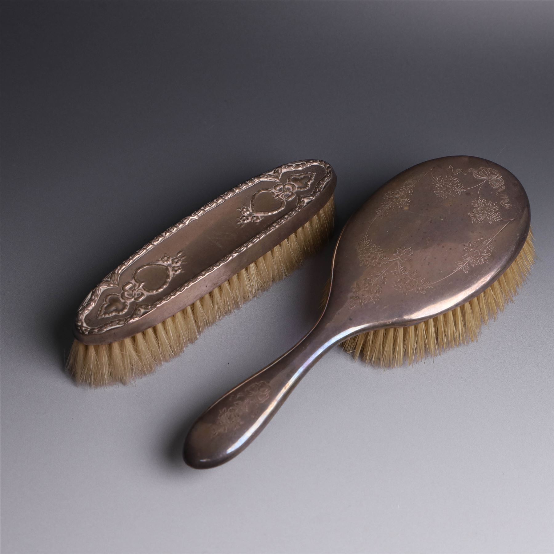 Early 20th Century silver mounted dressing table set, comprising hand mirror, shoe horn and a button hook, each with engraved floral decoration, together with a silver mounted hairbrush and clothes brush, all hallmarked