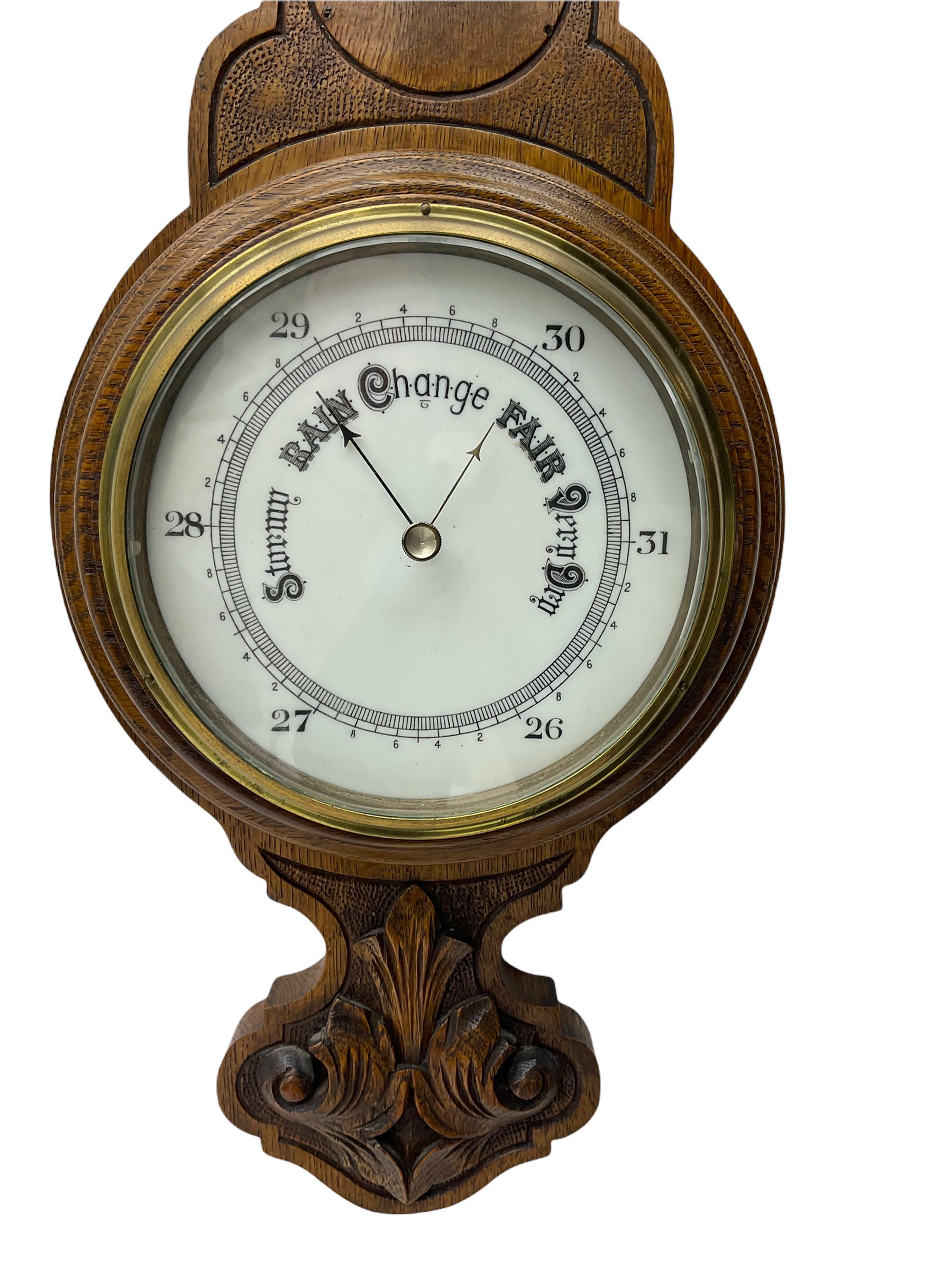 An English 1930’s solid oak carved hall barometer in a scroll shaped