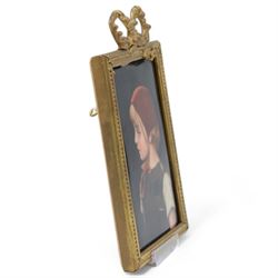 Late 19th/early 20th century German hand painted porcelain plaque, depicting a young girl in a red bonnet, after a painting by Gabriel Schachinger, within a beaded gilt frame with bow surmount, bearing paper label for Kunstinstitut fur Porzellan-Malerei Merkel-Heine Wiesbaden verso, and further paper label indistinctly inscribed '286 [...] Schachinger', also impressed 107, not including bow 16cm x 11.5cm
