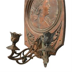 Pair of late 19th/early 20th century Art Nouveau copper twin branch wall sconces, each with shaped back plate chased with a central panel of a maiden in profile above and surmounted by foliate motifs, supporting two foliate open cast branches with bud sockets above conforming drip pans, H31cm W16cm D8.5cm
