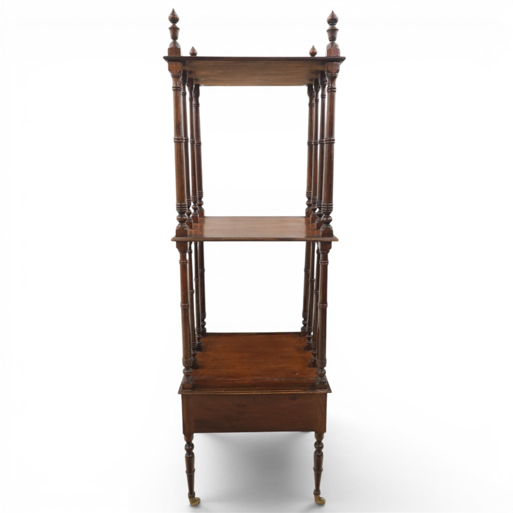 Late Victorian mahogany whatnot, the three tiers supported by turned spindle uprights with turned finials, fitted with a single frieze drawer, raised on turned supports with brass castors