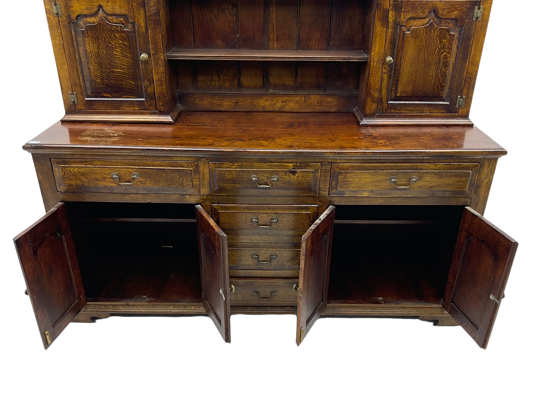 Traditional oak dresser, the moulded cornice over shaped apron, three heights plate rack fitted with two cupboards, the base fitted with six drawers and two double cupboards, panelled pointed ogee arched doors, on bracket feet
