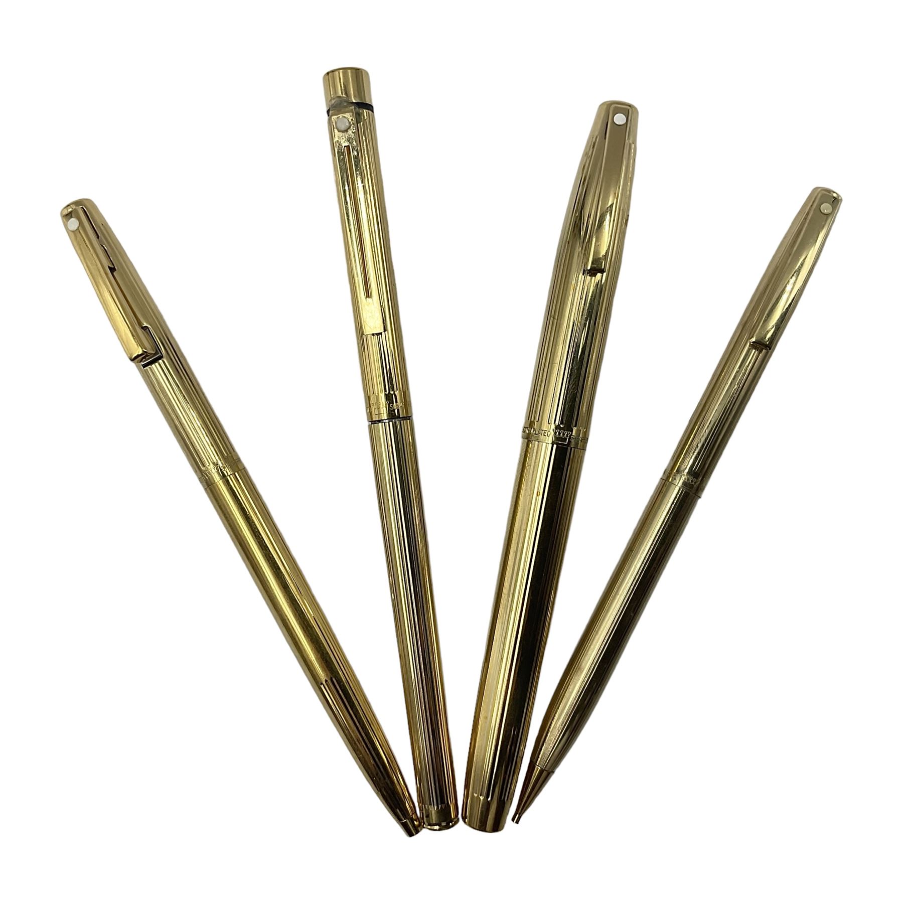Sheaffer Triumph Imperial fountain pen, the gold plated barrel with fluted stripe design and gold nib stamped 14K 585, together with a Sheaffer Targa slimline fountain pen with gold plated barrel similarly decorated with gold nib stamped 14K 585, ballpoint pen and propelling pencil, each with a fluted gold plated barrel, largest L13.5cm (4)