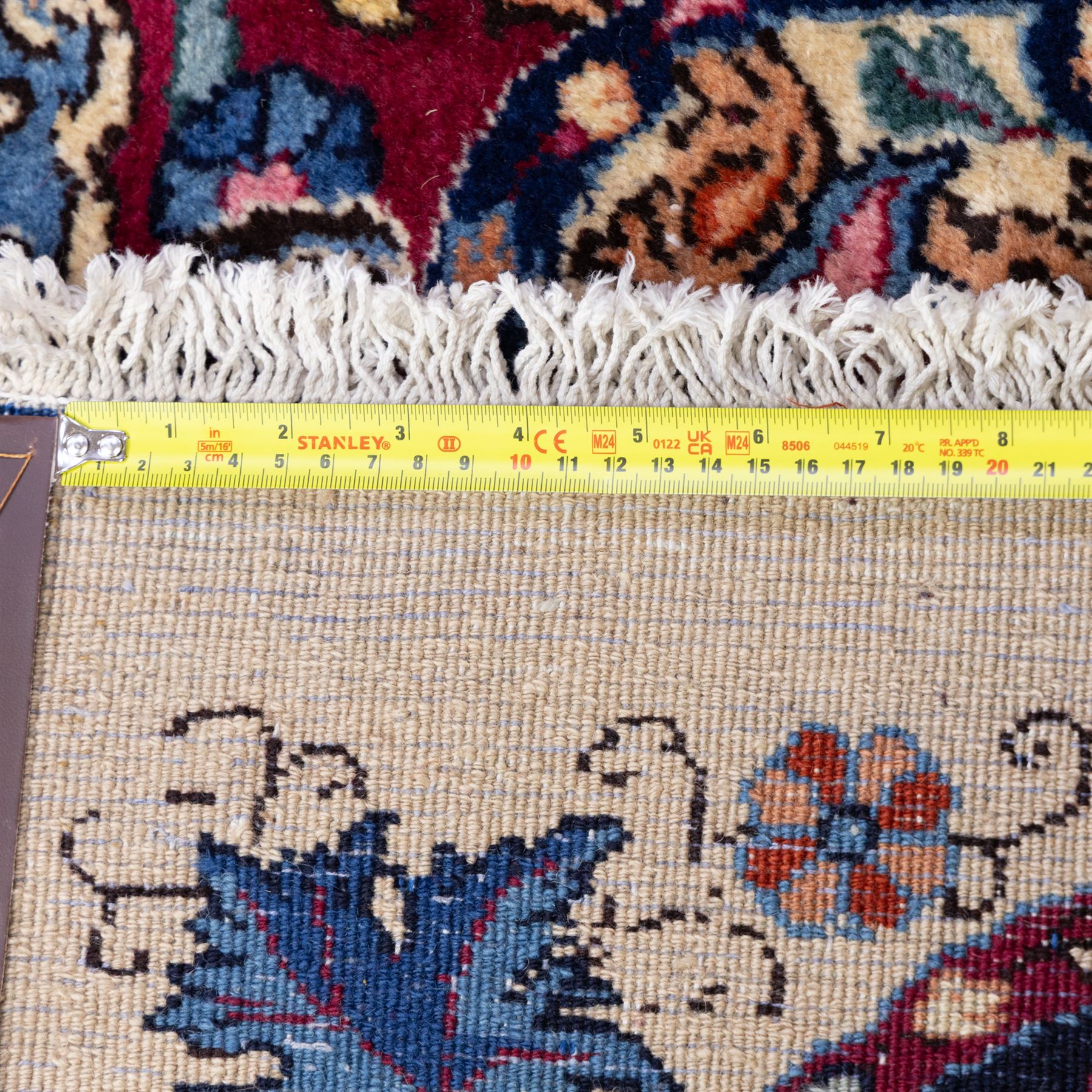 Large North East Persian Meshed hand-knotted carpet with signature, raspberry red field with central shaped cusped medallion, densely decorated with intricate arrangement of scrolling vines, and florals designs within conforming spandrels and a dark ground border richly ornamented with stylized flowers, vase and bird ornamentation, enclosed by guard stripes, with cotton fringe ends