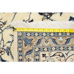 Central Persian Nain hand-knotted carpet, ivory field with central radiating medallion, issuing an all-over design of scrolling vines, palmettes, and delicate floral sprays with conforming spandrels, enclosed by a foliate border, framed by multiple guard stripes, with cotton fringe ends 