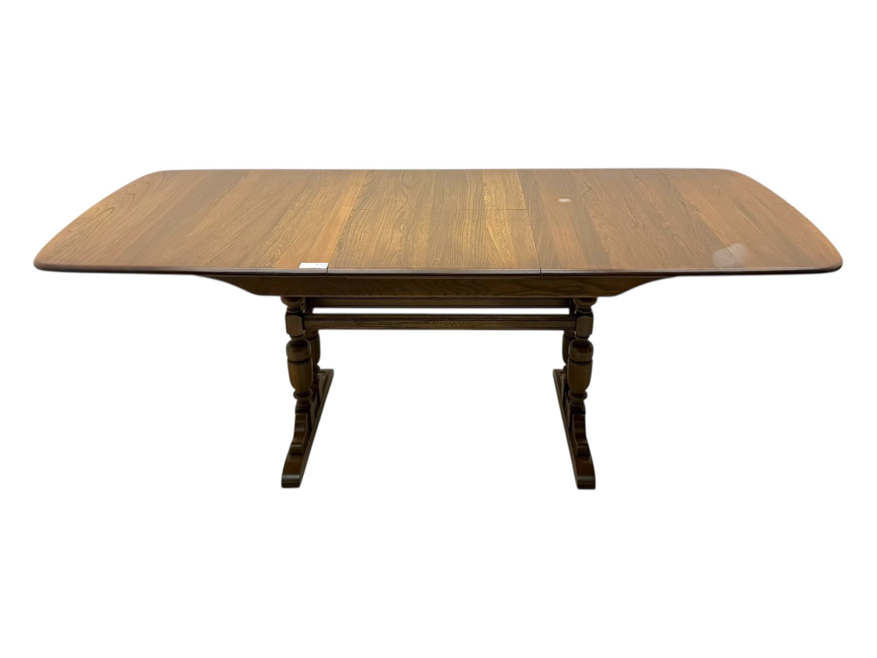 Ercol - late 20th century oak refectory dining table, rectangular top with rounded corners and central extending leaf, raised on turned baluster supports united by a stretcher (Extended 200cm)