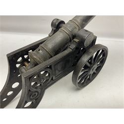 Victorian cast-iron and steel signal cannon, approximately half-inch bore, with 23cm ringed barrel and cylindrical trunnions, on a cast iron carriage with two twelve-spoked wheels and guilloche pierced swept back support, L43cm overall