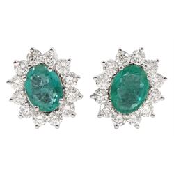 Pair of oval emerald and round brilliant cut diamond cluster stud earrings, stamped 18K, total emerald weight approx 3.15 carat, total diamond weight approx 2.40 carat